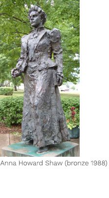 A statue of a woman in a dress stands on top of a pedestal.