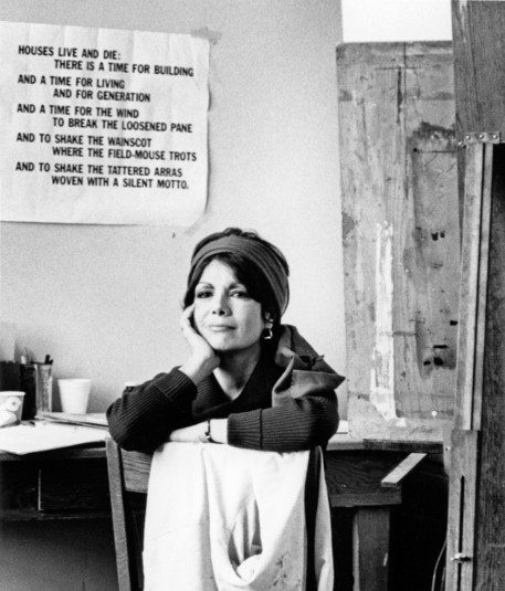 A woman in a hat and gloves standing next to a table.