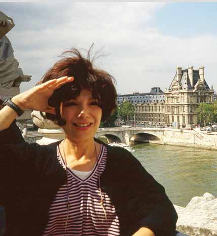 A woman saluting in front of the louvre museum.