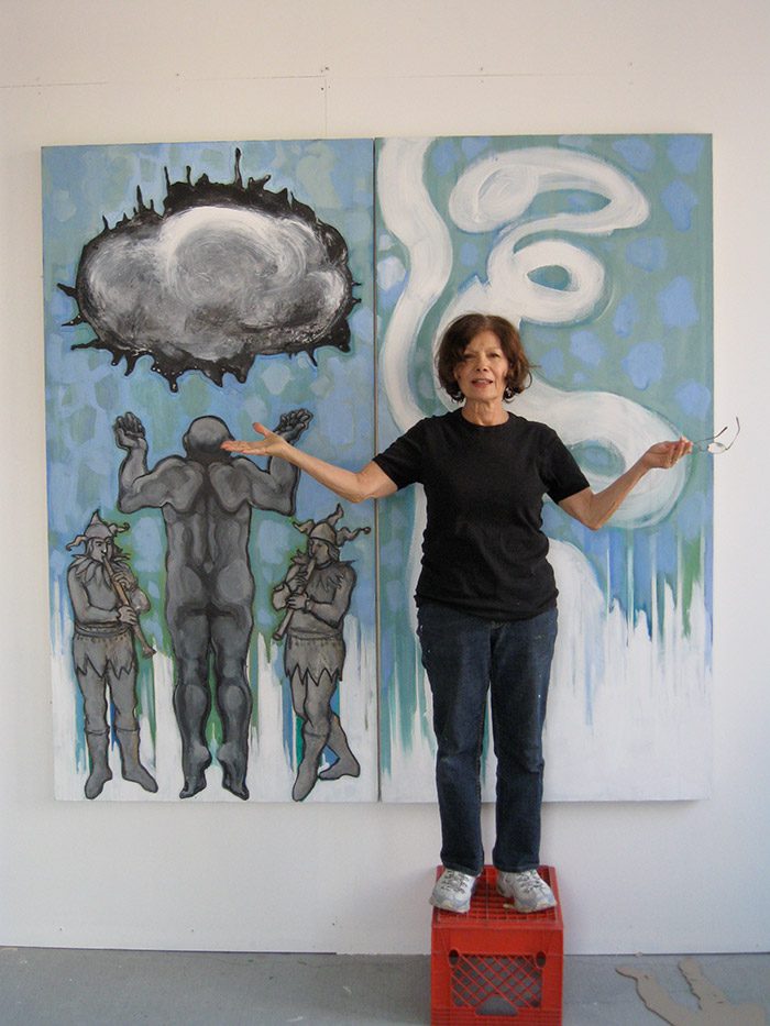 A woman standing in front of two paintings.